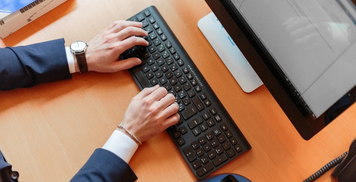 personne en costume en train de taper sur un clavier d'ordinateur fixe
